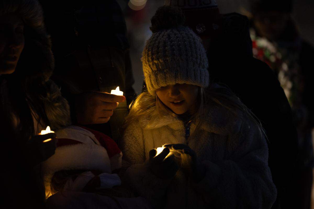 Members of the Musick family light electric candles during the candlelight vigil for those who lost. 