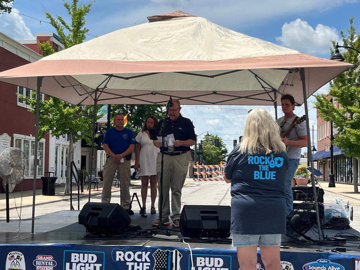 Fairview Heights Mayor Mark Kupsky speaks at a Rock the Blue fundraiser on Saturday in downtown Belleville. Joining him on stage are, left to right, Fairview Heights Police Chief Steve Johnson, Rachel’s Sidebar owner Rachel Speichinger and singer-songwriter Ethan Carl.