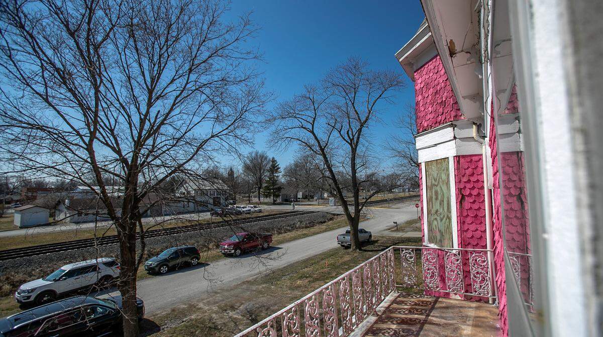 An upstairs bedroom has a door to a balcony on “The Pink House.” It overlooks railroad tracks and a smattering of businesses and village buildings in downtown Aviston.