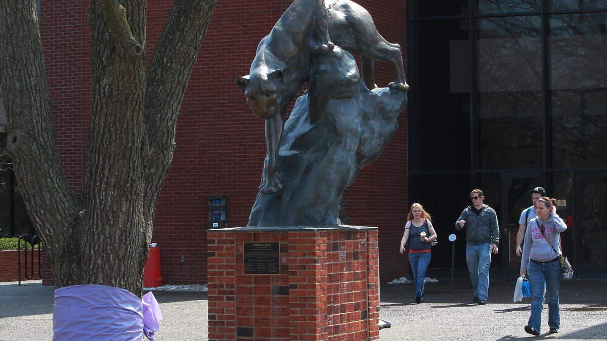 File: Southern Illinois University Edwardsville students walk past the campus’ cougar statue. The university plans to layoff employees and drop academic programs to cut costs.