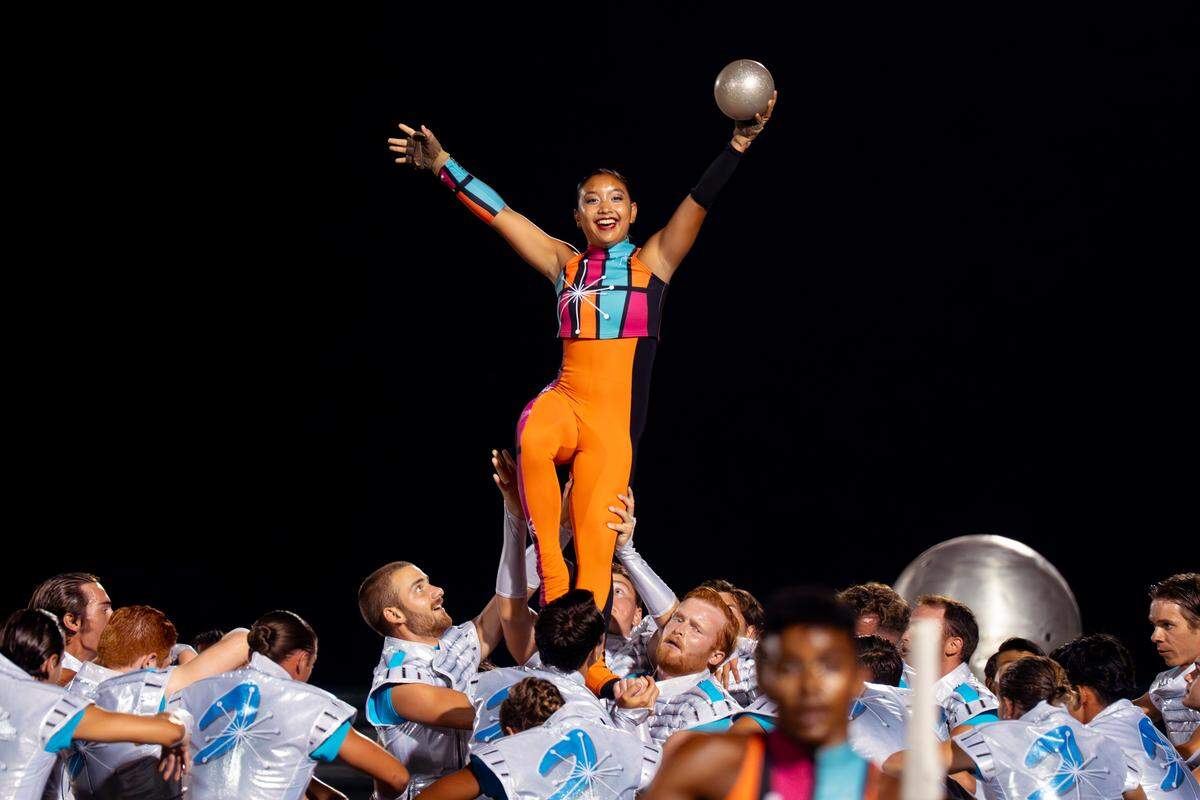 A Boston Crusaders color guard member is lifted into the air by the drum corps’ hornlike during a performance of their production “BOOM” at Belleville West High School on Tuesday, July 22, 2025, in Belleville. The Massachusetts-based group took first place at the competition.
