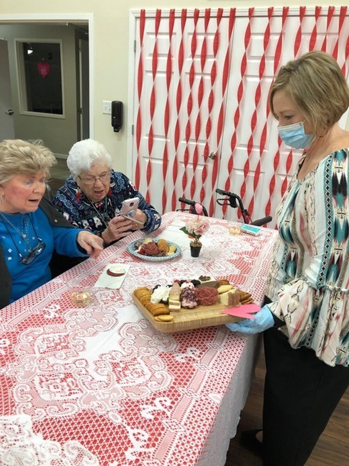Cedarhurst of Highland residents Norma Holtz and Joan Sacket take pictures of the finish board with Cedarhurst of Highland’s Director of Sales Mae McNamee during a virtual charcuterie event hosted by Candi Graves of Grazeful Gatherings in Columbia.