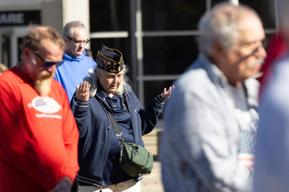 Bowed heads and raised hands during a benediction performed by Belleville police chaplain Ralph Holmes during Belleville’s 26th annual Veterans Day ceremony on Nov. 11, 2024.