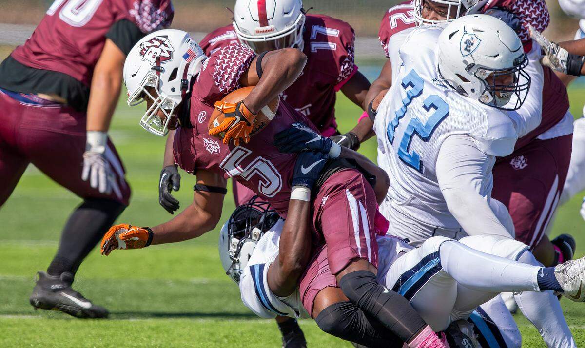 Belleville West’s Jahkori Adams carries the ball while under pressure during Saturday’s Southwestern Conference game against Belleville East. The Lancers ultimately prevailed 41-0.