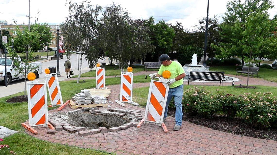 Workers remove the pedestal that formerly held the bronze Ninian Edwards statue in the park at the corner of St. Louis and Vandalia streets in Edwardsville on Monday morning.