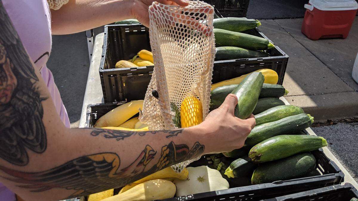 An Old Town Farmers Market visitor places fresh zucchini in a bag during a recent Saturday morning.