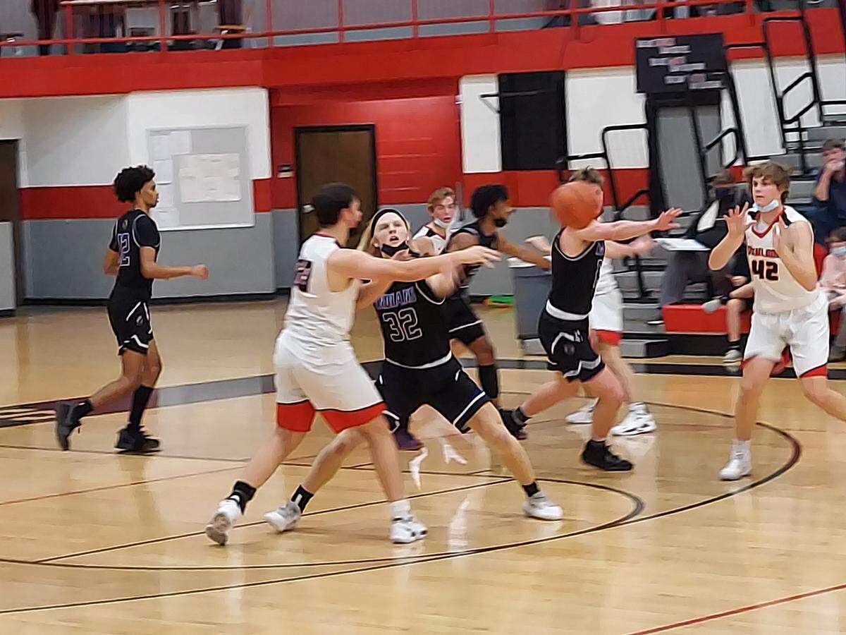 Highland’s Joe Jansen flips a pass cross-court to teammate Gunnar Mackey as Jansen is guarded by Mascoutah senior center Tommy Beck (32) during the Mississippi Valley Conference opener for both teams Friday, Dec. 3, at Highland High School. The Indians ultimately defeated the Bulldogs 56-47.