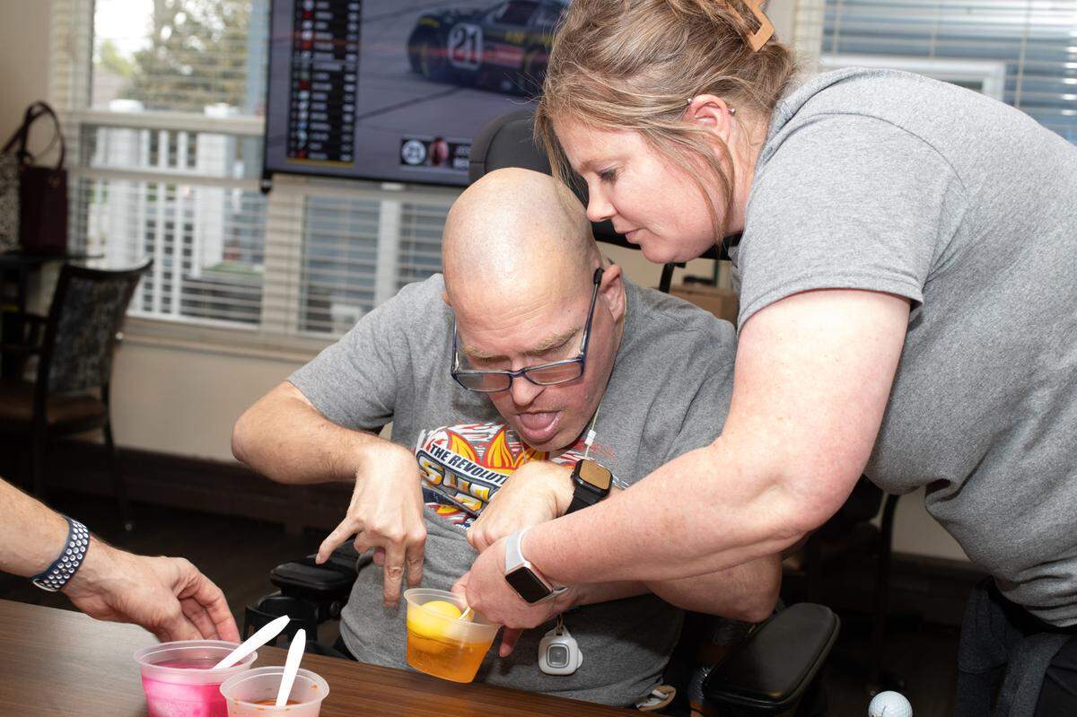 Bri Wellen, an employee at Clinton Manor Living Center, helps a resident paint an Easter egg the Friday before Easter. The facility cares for a total of 88 residents, including 51 adults who have developmental disabilities.