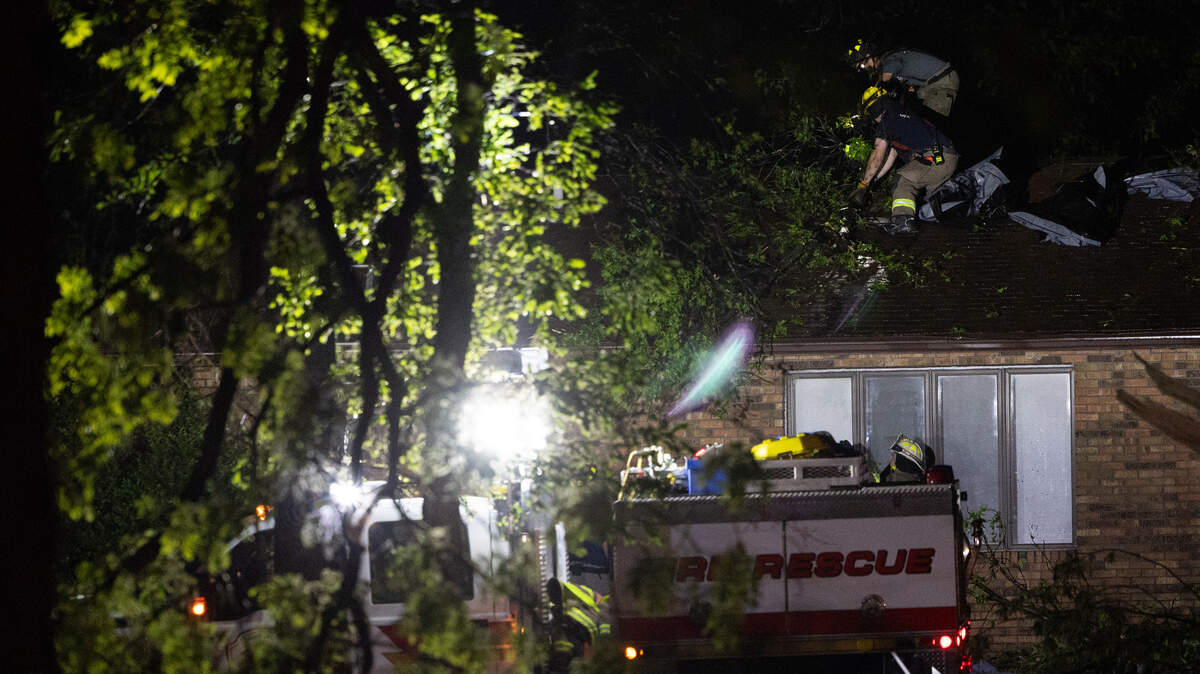 Fire crews check a house along IL 160 between Trenton and New Baden, where a likely tornado damaged homes and downed power lines Monday.