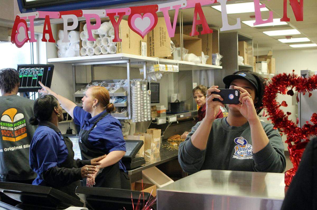 An employee at the Belleville Crossings White Castle pauses to take a photo of the wedding inside the White Castle Friday.