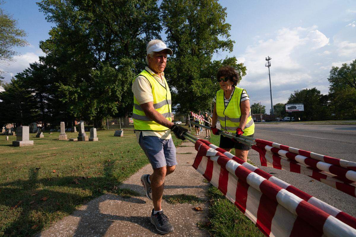 Rick Bozanich leads a member of the Belleville Running as they place flags along a funeral route as part of a homecoming for a fallen servicemember on Sept. 21, 2023.