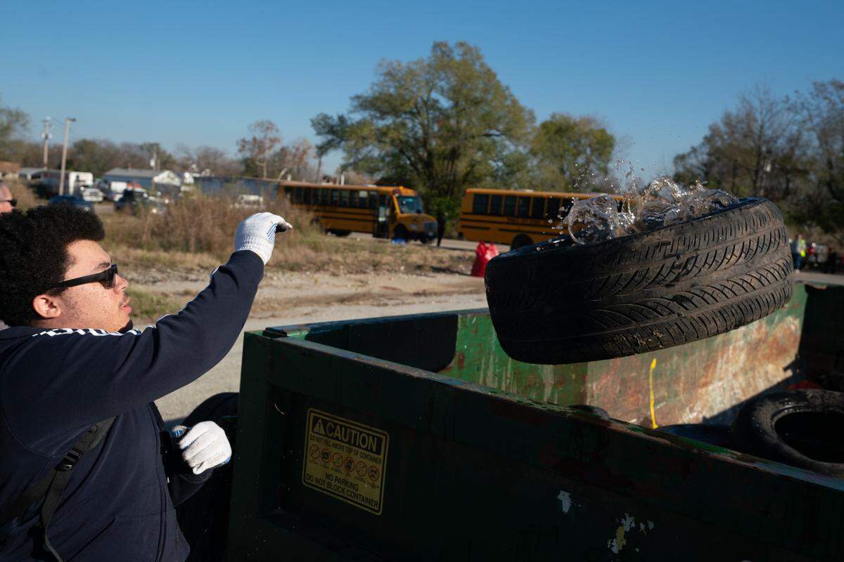 Tires were in abundance at the illegal dump site, such as this one currently being thrown into the dumpster. Eventually volunteers were told to stop picking up tires, as landfills often charge penalties for accepting them.