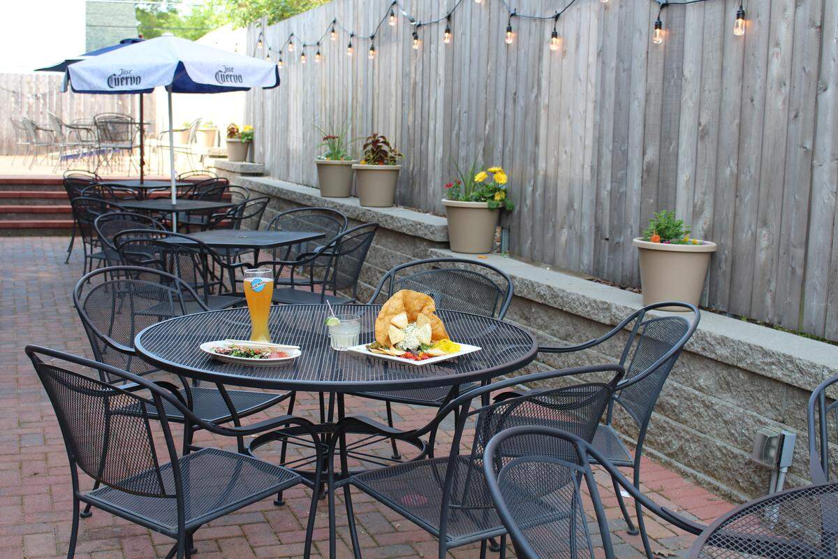 The large tiered patio at The Cobblestone Eatery and Drinkery in Lebanon has black wrought-iron umbrella tables, potted plants and Edison-style light bulbs hanging along its wooden fence.