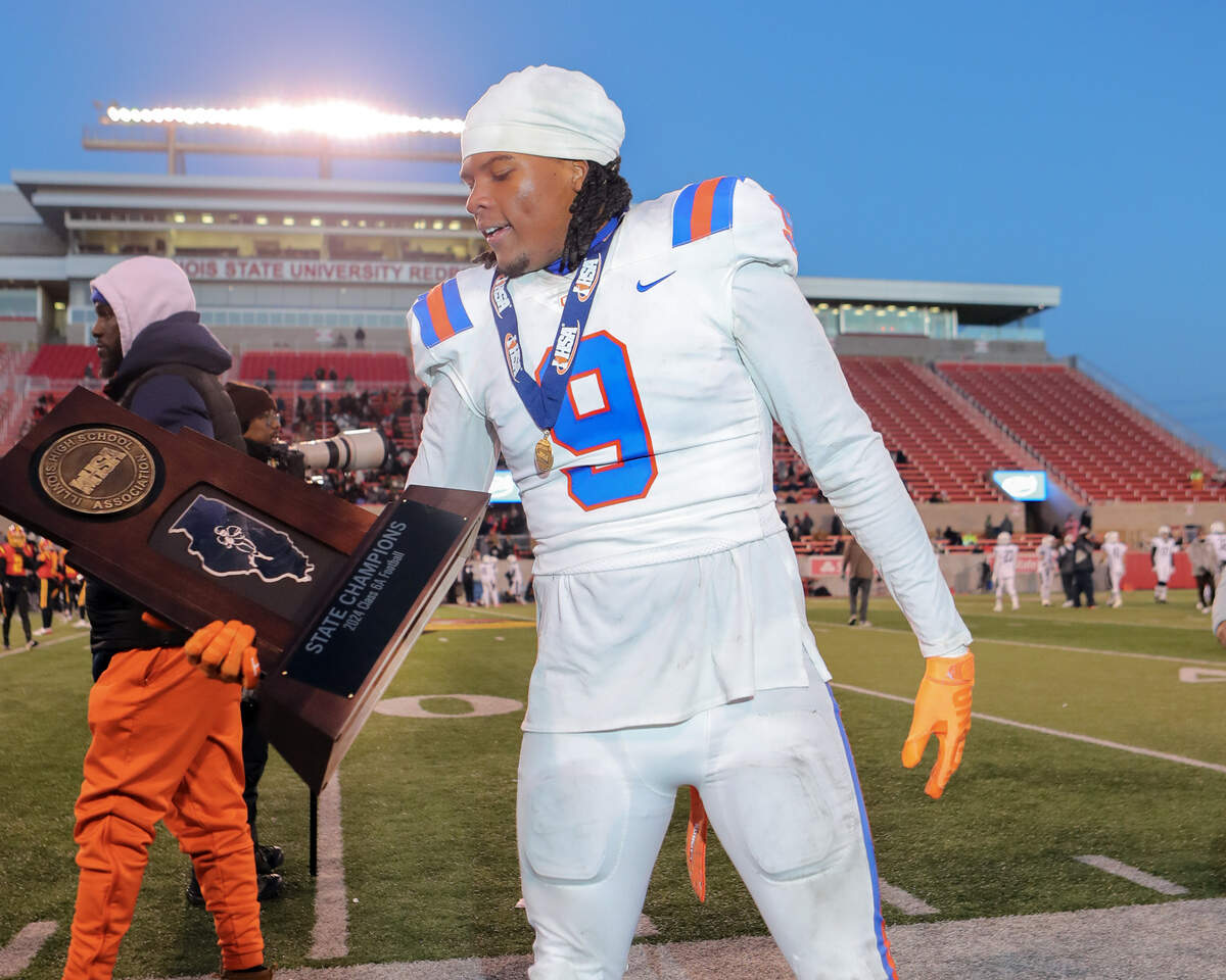 East St. Louis’ Keandre McClendon with the championship trophy after defeating Geneva 48-28 in the Illinois Class 6A championship game at Hancock Stadium on the campus of the Illinois State University.