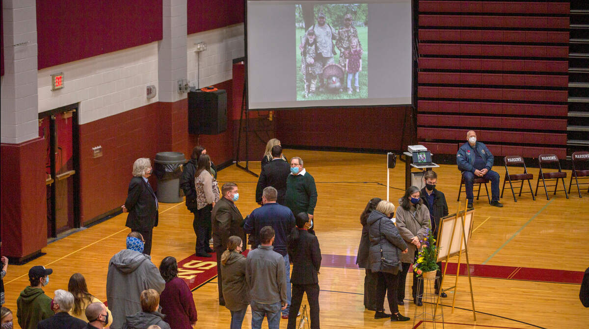 A slideshow of memories projects on a screen as Friends, family and students of Belleville West High School teacher Bob Flake attend a visitation held inside the school gymnasium on Saturday. Flake, who died on Dec. 30, was the head of the school’s science department and he had previously served as offensive coordinator for the football team. He was 40.