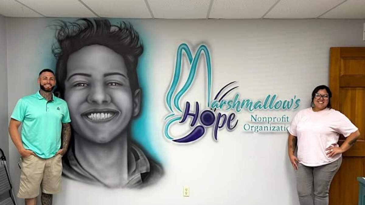 Tattoo artist Ryan Robison and Laura Kane, Marshmallow's HOPE founder and executive director, stand by a completed wall mural featuring Kane's son, Zachary.