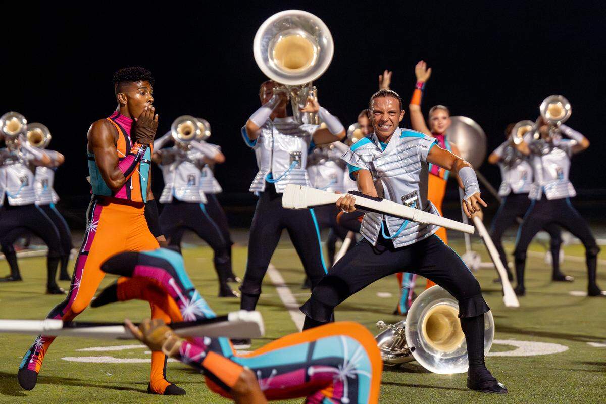 Boston Crusaders contra player Jackson Mettey, 21, of Fayetteville, Arkansas, reacts as he catches a rifle after playing a solo during the corps’ “BOOM” performance at Belleville West High School on Tuesday, July 22, 2025, in Belleville.