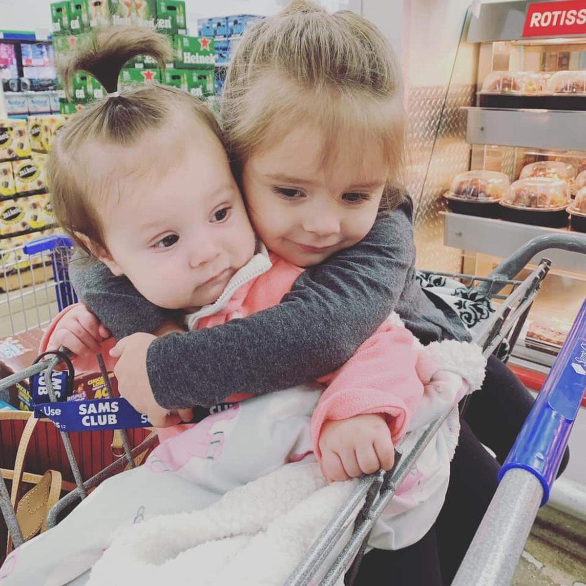 Two-year-old Layla Thomas hugs her 8-month-old sister, Adilynn Thomas, in a grocery cart. They are the daughters of Victoria Aubuschon and C.J. Thomas, of Belleville.