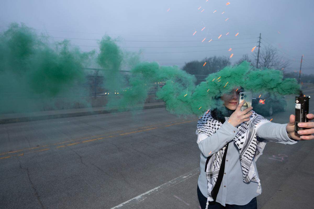 A demonstrator lights green fireworks on the Bunkum Road bridge over Interstate 64 in Fairview Heights to protest the ongoing conflict in Gaza on Feb. 2, 2024.