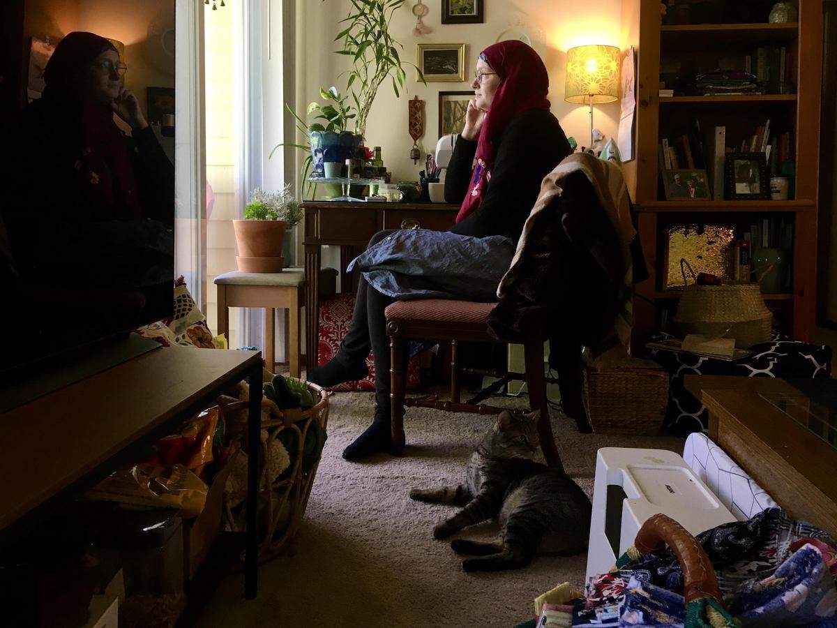 Recovered COVID-19 patient Melissa Stone and her cat Long Boi spend time in her St. Charles apartment. Stone has begun sewing cloth masks.