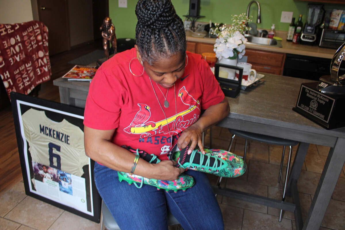 Sukeena Gunner holds a pair of football cleats that belonged to her son, Jaylon McKenzie. Jaylon, 14, died in 2019 after shots rang out at a house party in Venice.
