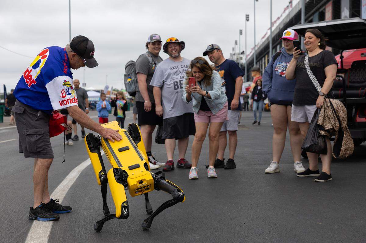 Fans stop to appreciate a robot dog from Boston Dynamics during the first day of the Enjoy Illinois 300 Cup Race at WorldWide Technology Raceway in Madison, Ill. on June 1, 2024.