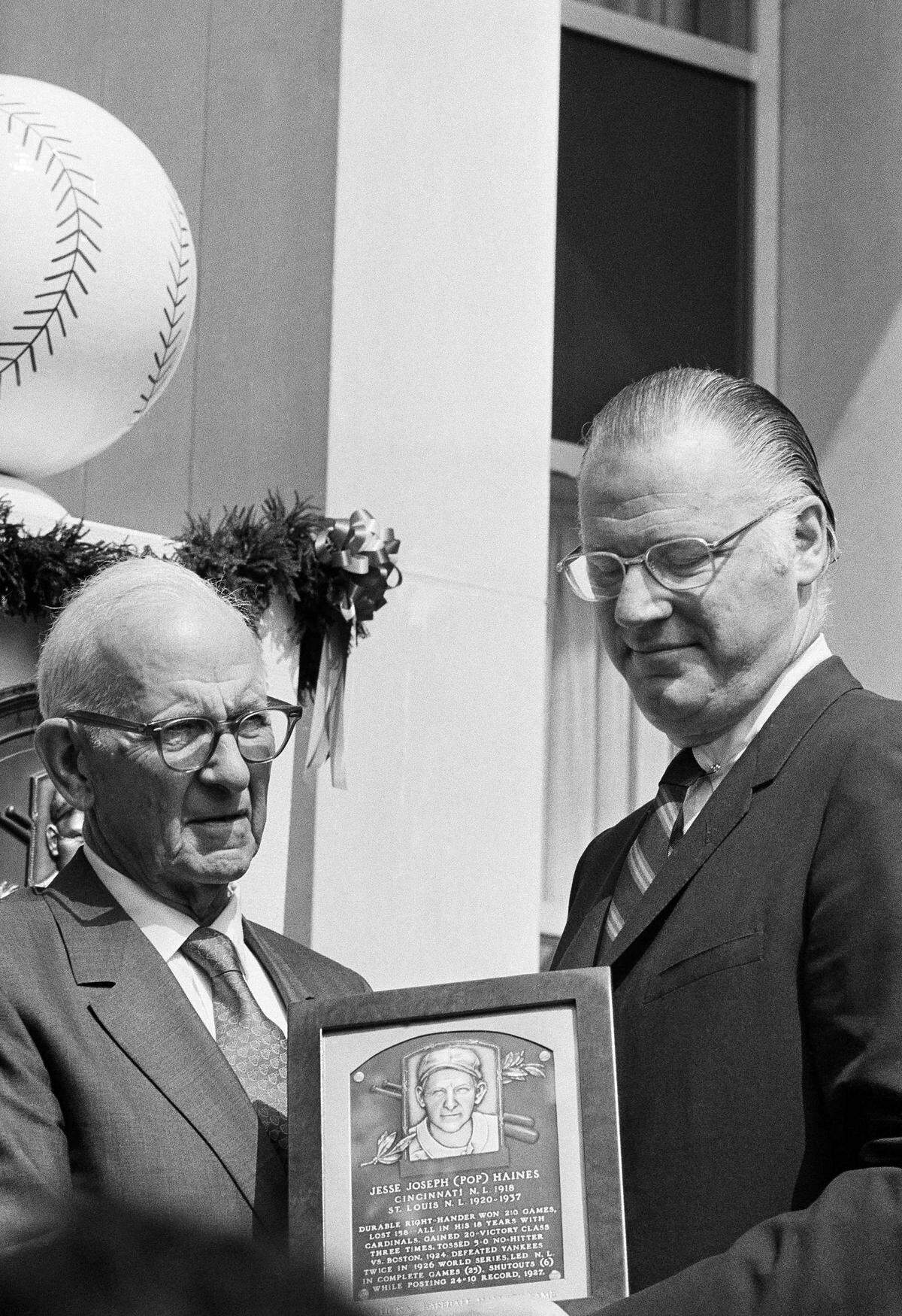 Baseball Commissioner Bowie Kuhn, right, presents plaque to Jesse (Pop) Haines, the former Cincinnati and St. Louis pitcher, during induction ceremonies for baseballs Hall of Fame at Cooperstown, N.Y., on July 27, 1970. (AP Photo/RH)