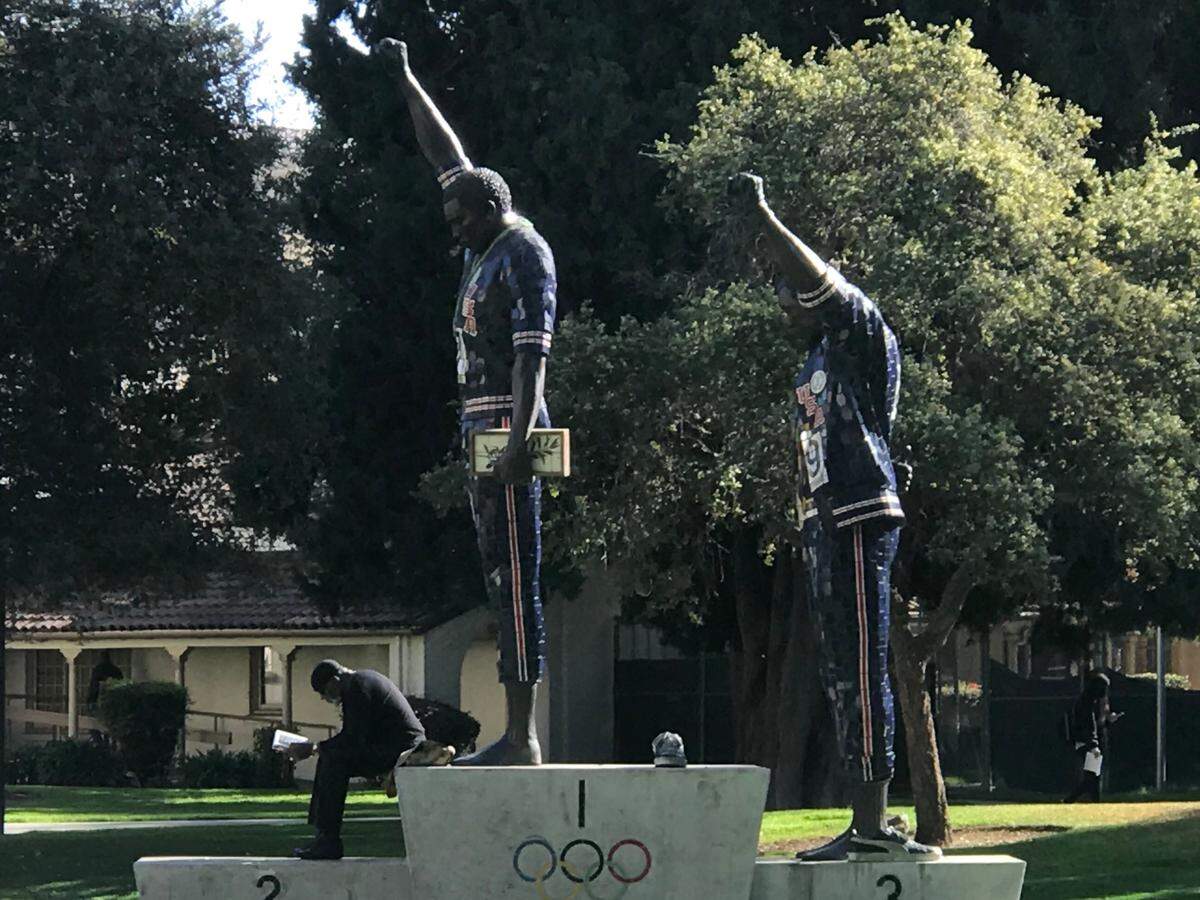 Dr. Harry Edwards sitting on a sculpture dedicated to Tommie Smith and John Carlos at his alma mater, San Jose State University