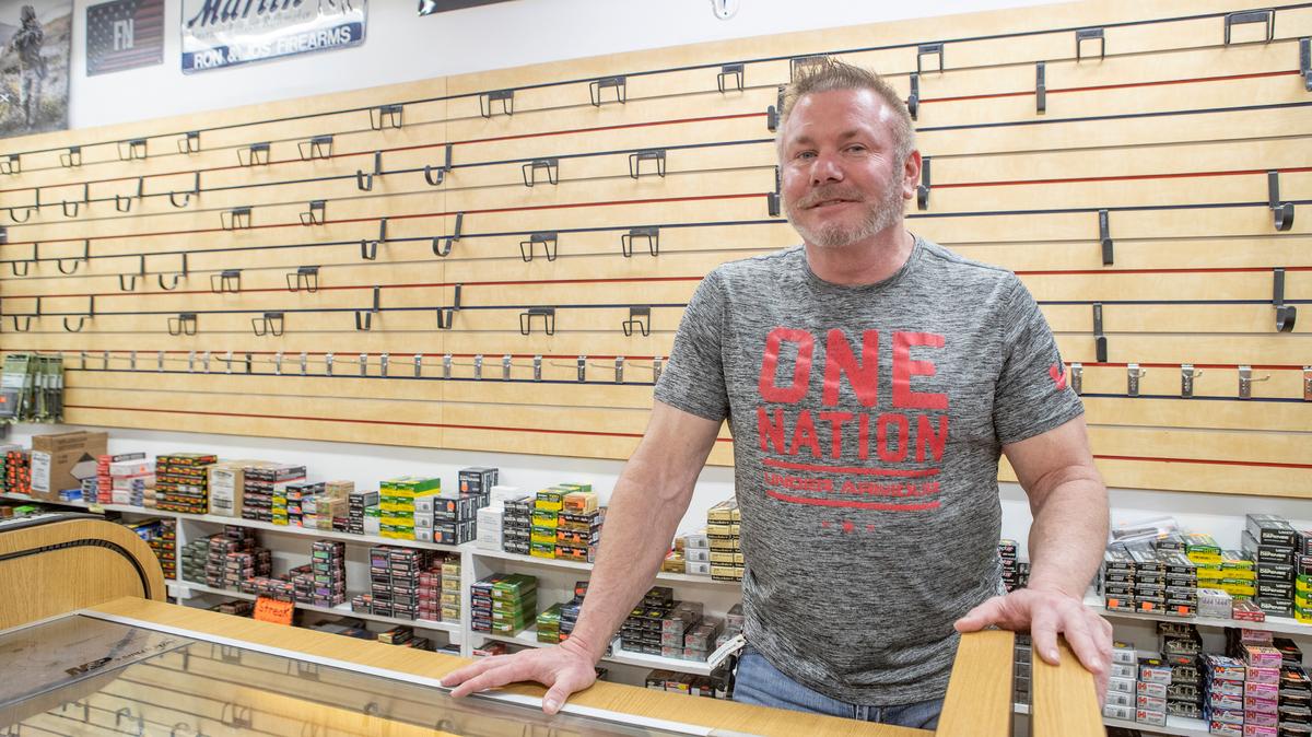 Ron Gompers, president of RON & JO’s Firearms & Sporting Supplies II, Inc. in O’Fallon, Illinois stands near a empty wall that contained accessories that are now banned under the new Illinois Law.