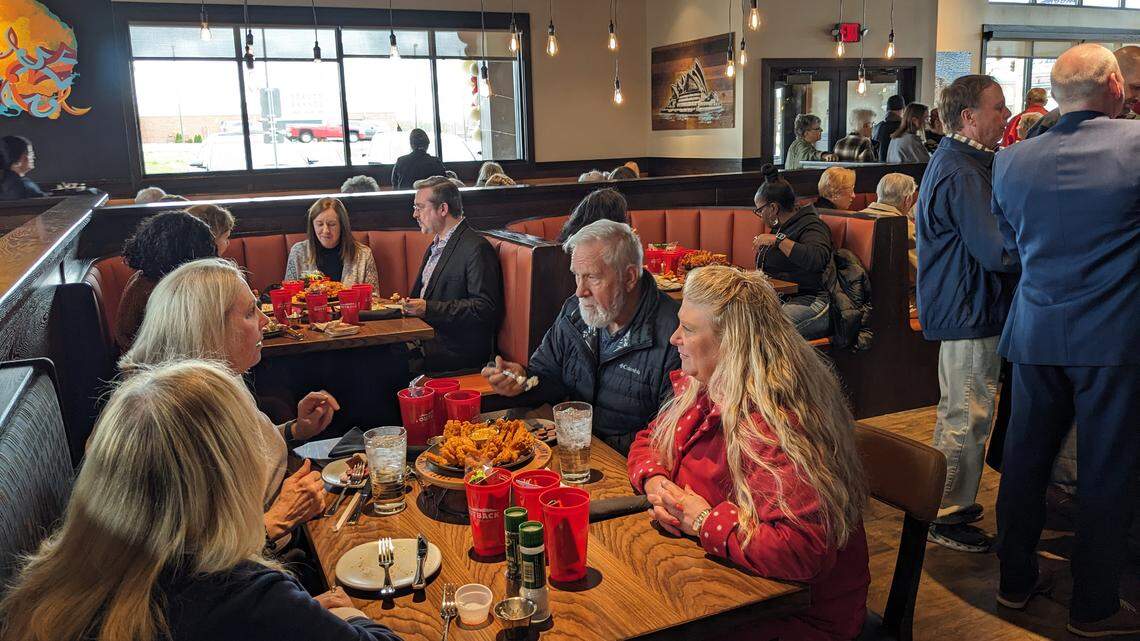 Guests enjoy complimentary food offerings at the ribbon-cutting event for Outback Steakhouse in O’Fallon.