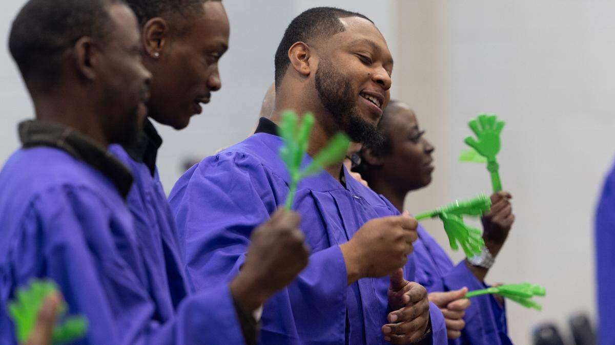 Graduates of the Illinois Climate and Equitable Jobs Act (CEJA) Workforce Training Program use noise makers during their graduation ceremony. Participants undertook an extensive training program in property weatherization or solar panel maintenance and installation.