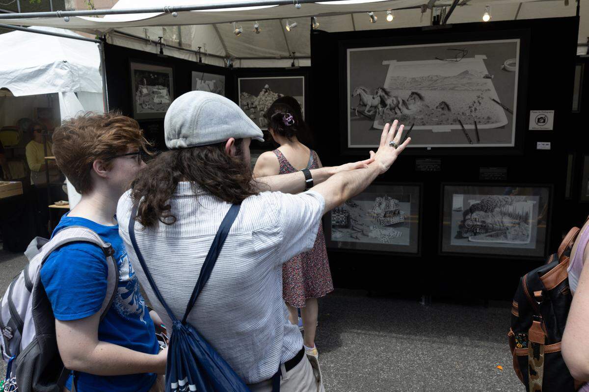 Visitors to Belleville’s Art on the Square in 2024 discuss artwork.