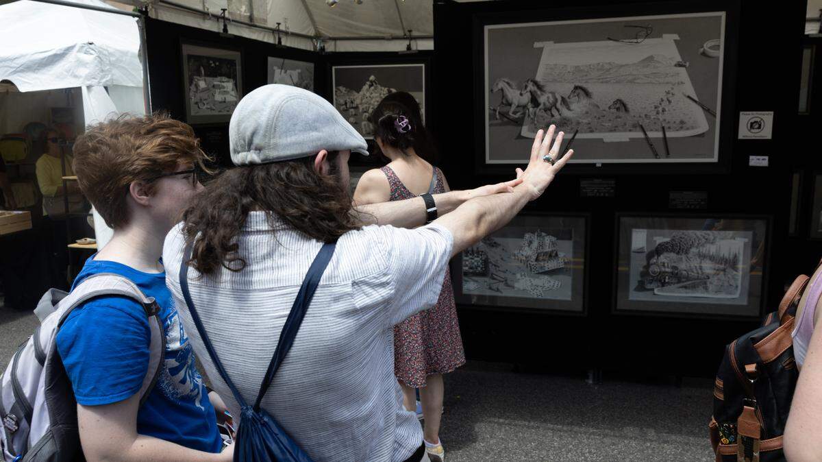 Visitors to Belleville’s Art on the Square discuss an artwork on May 18, 2024.