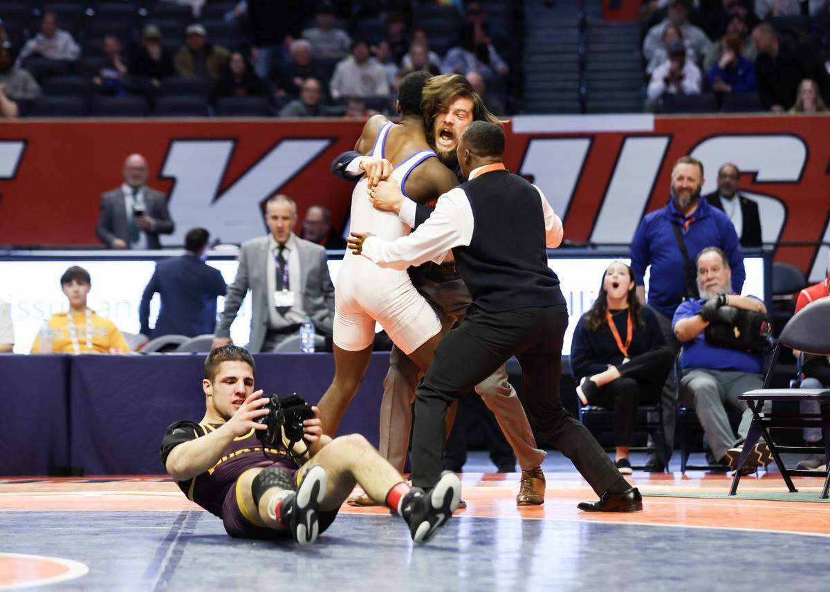 East St. Louis’s Pierre Walton and head coach Stephen Doty celebrate Walton’s win against Montini’s Santino Tenuta in the Class 2A 165-pound championship match at the IHSA Individual Wrestling State Finals on Saturday.