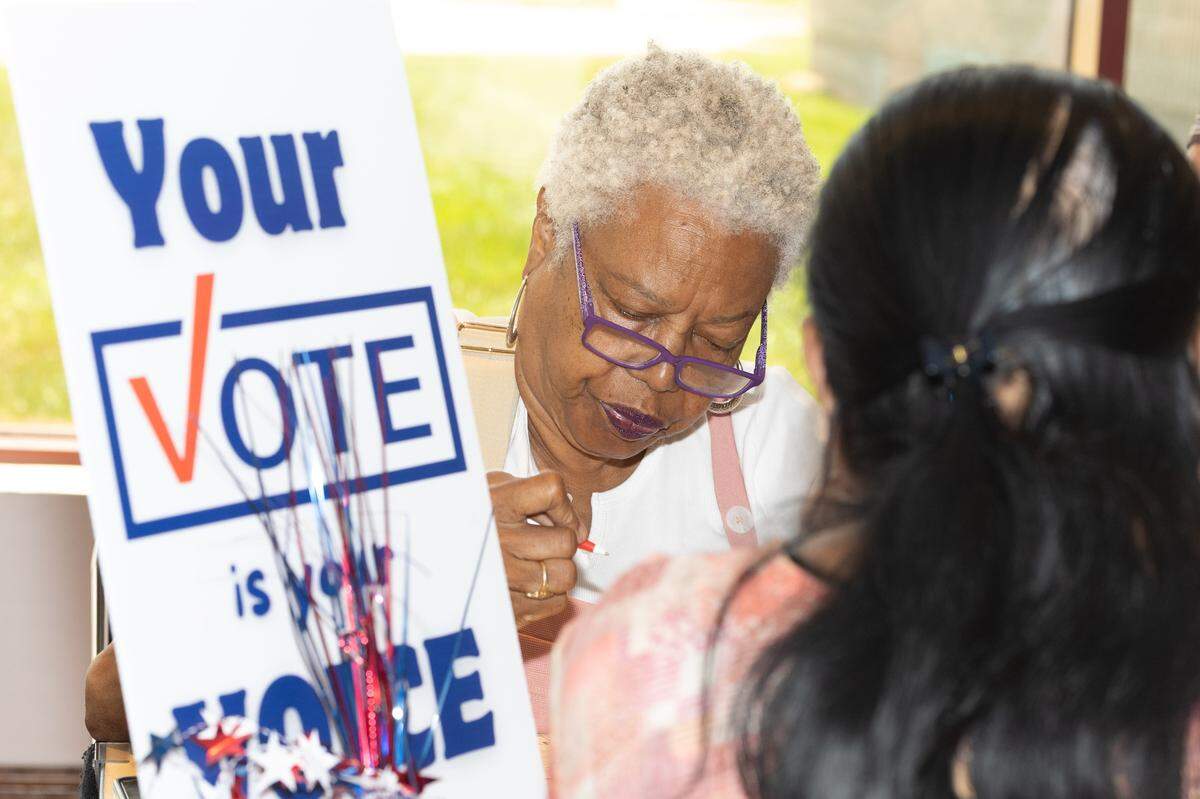 Debra Pitts helps a newly sworn U.S. citizen register to vote following a naturalization ceremony in Collinsville.