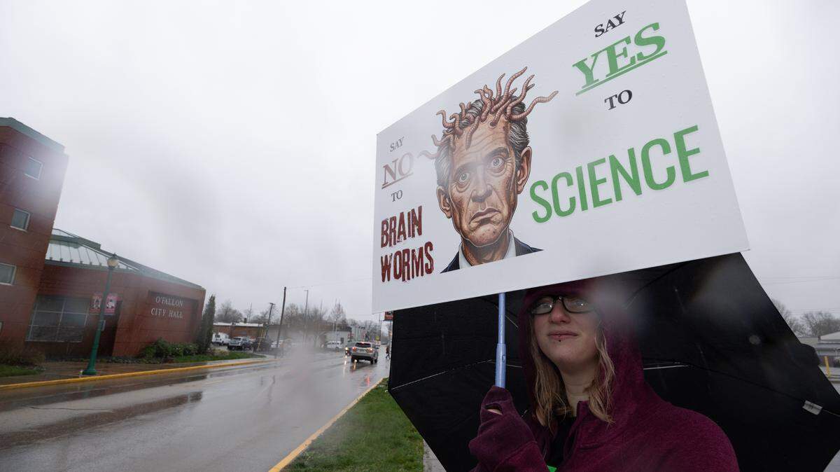 An organizer holds up a sign at a Hands Off! protest in O’Fallon. More than 400 people showed up in protest against the Trump administration on Saturday.