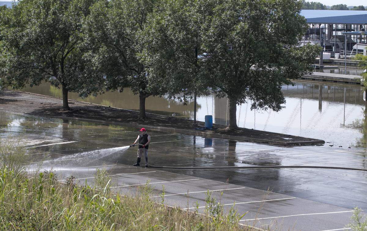 As floodwater slowly creeps back into Mississippi a worker cleans the parking lot to the Alton Marina. Work crews were busy around Alton Thursday removing sandbags and temporary flood walls as cleanup efforts continue in the area.