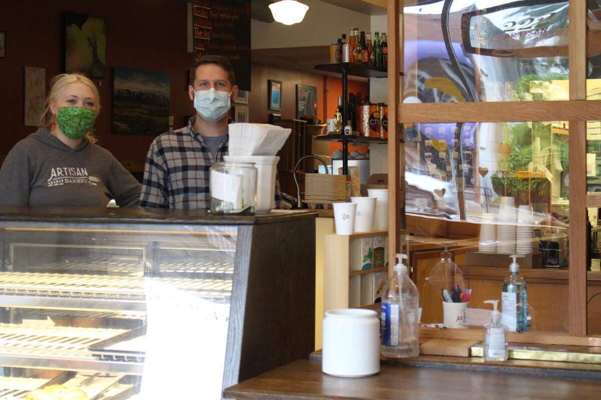 Baristas Kristin Campbell, left, and Josh Lawson wear masks and take orders from behind a plexiglass window at 222 Artisan Bakery & Cafe in Edwardsville in mid-May to help slow the spread of the coronavirus.