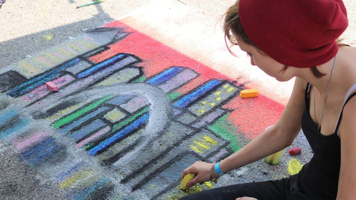 Deslarue Clark adds to her chalk drawing of a St. Louis, Chicago skyline combo during the Highland Street Art Festival in 2017. The event will again take place even without funding from the city.