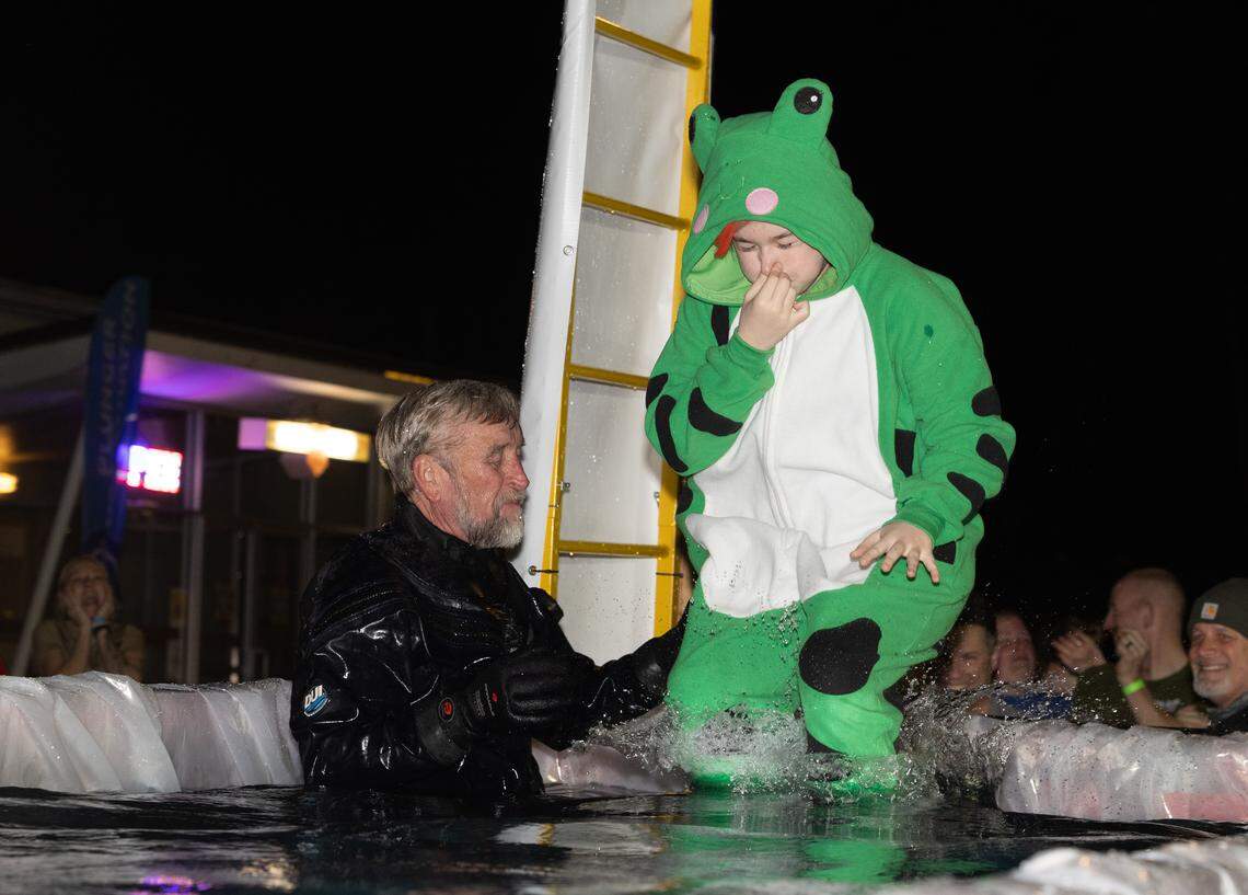 A frog costumed plunger is helped into the dumpster as part of the Polar Plunge Friday in Collinsville.