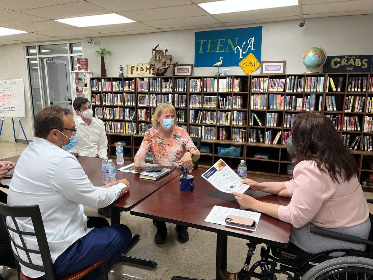 U.S. Sen. Tammy Duckworth, right, discusses broadband internet with Fairmont City Mayor Michael Suarez, front, and librarian Katie Heaton at the village library on May 13 as a Duckworth staffer looks on.