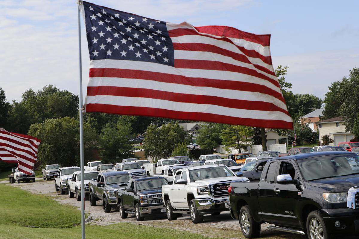 Trucks line up in Waterloo Saturday morning to collect large American flags that would later be placed along the funeral route of slain Illinois State Police Trooper Nicholas Hopkins. More than 100 volunteers lent their hands and vehicles to plant the flags throughout Waterloo.
