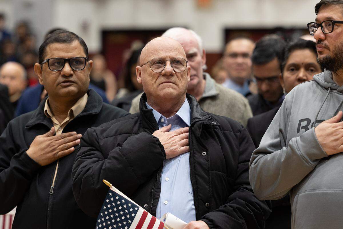 Newly naturalized American citizens take the Pledge of Allegiance for the first time during a naturalization ceremony at Belleville West High School Friday.
