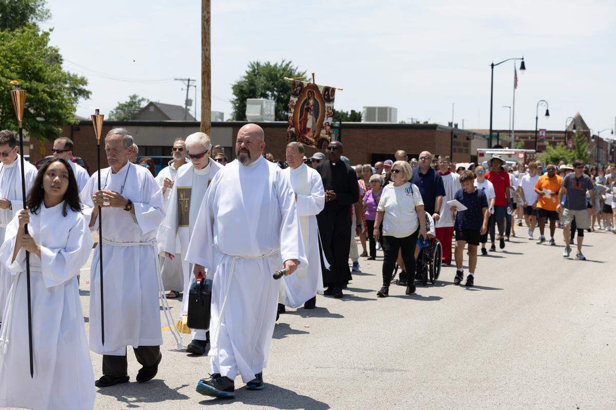 Hundreds of people march during a procession from St. Peter’s and Paul’s Catholic Church to a nearby cemetery of the same name in Collinsville, Ill. on July 8, 2024. The procession is part of a nationwide eucharist pilgrimage, with Catholics traveling from San Francisco to the endpoint of the pilgrimage, Indianapolis, picking up fellow pilgrims along the way.