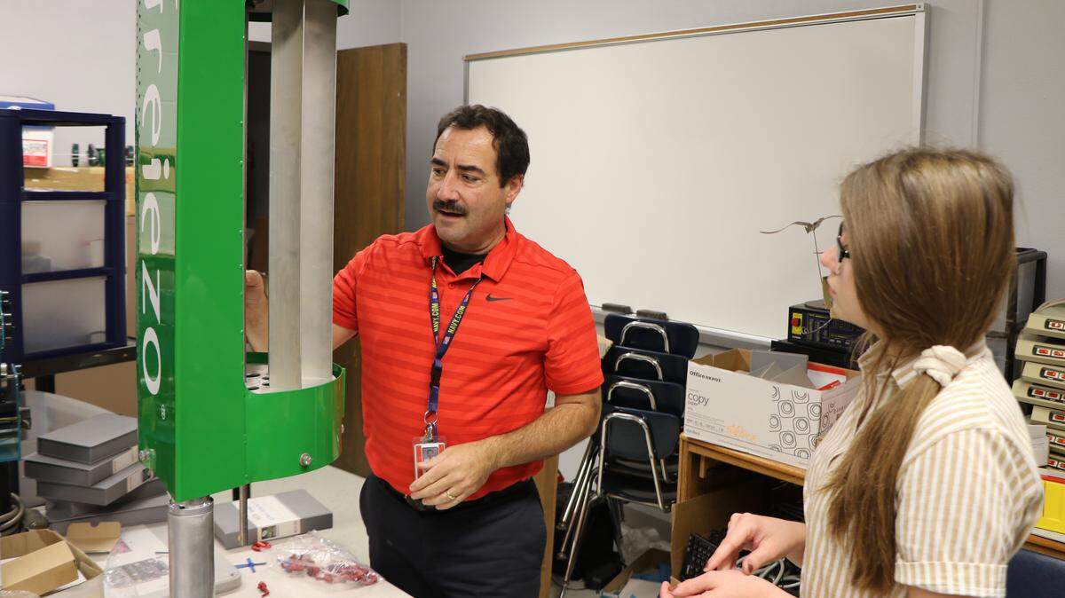 Highland High School teacher Chris Durbin, left, explains how a Freiezo wind power system works to GEMS club member and sophomore Elise LaRose. The GEMS club is set to host a renewable and alternative energy expo at the high school in late November, where they’ll host several energy companies from the Metro East.
