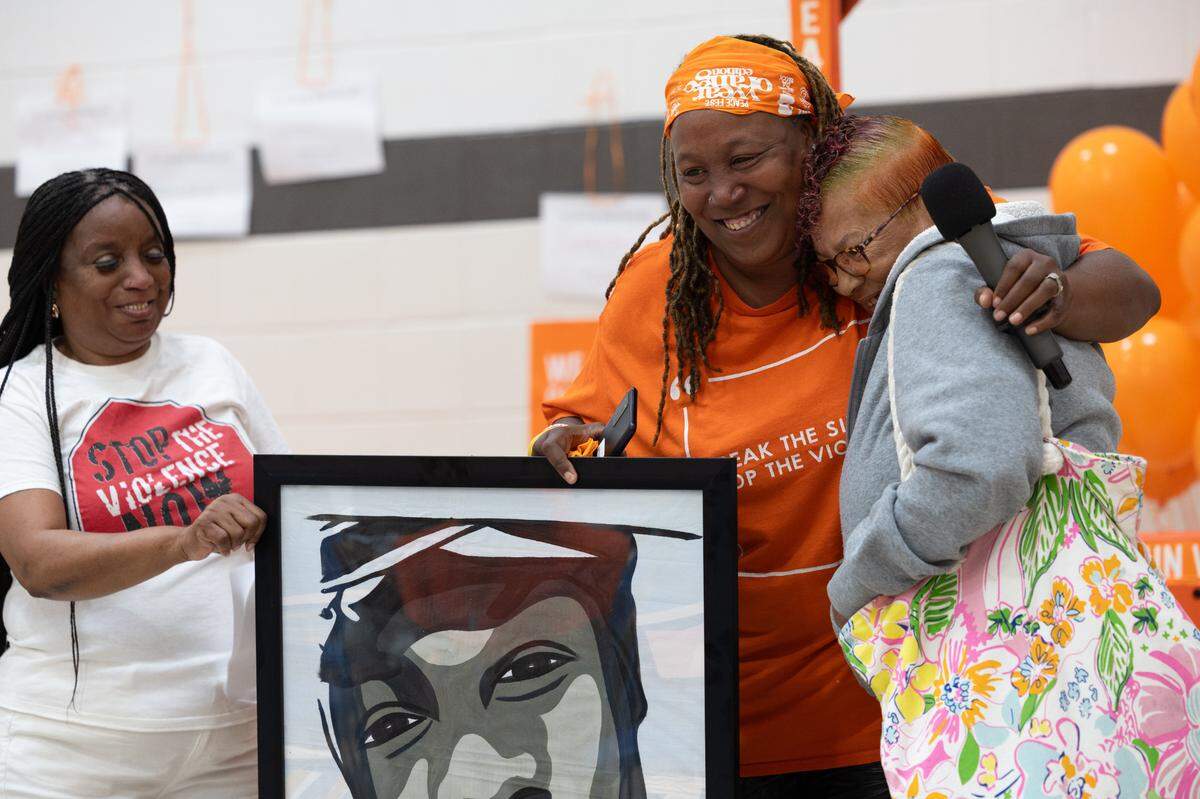 Skyler Pawnell smiles and hugs a member of Faces Not Forgotten, a nonprofit that links local artists with victims of gun violence to immortalize their loved ones in the form of portraits, after receiving one herself.