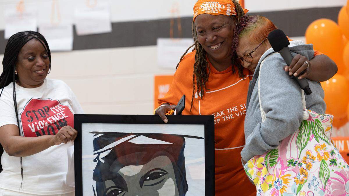 Skyler Pawnell smiles and hugs a friend as they display a portrait from Faces Not Forgotten, a nonprofit that links local artists with victims of gun violence to immortalize their loved ones in the form of portraits, after receiving one herself.