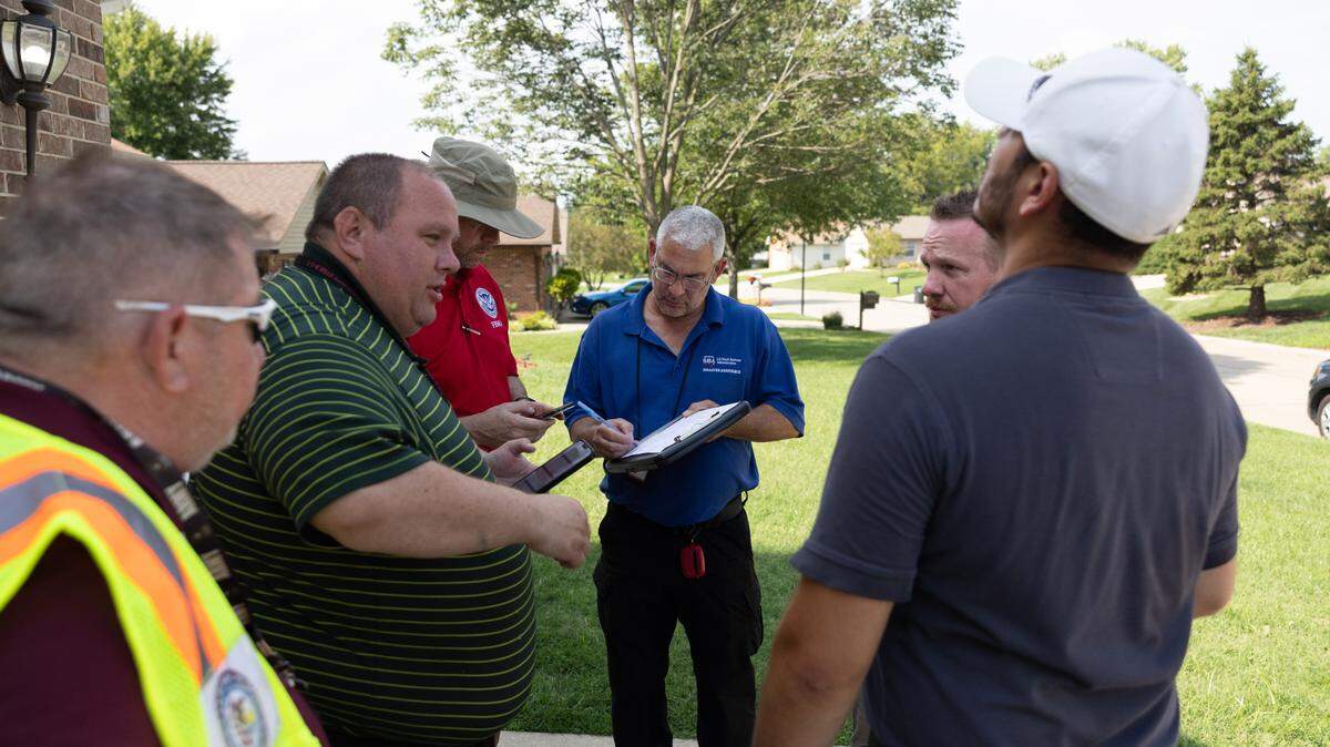 Representatives of federal, state and local officials gather outside of a Belleville house on July 30, 2024 to discuss effects of July flooding.