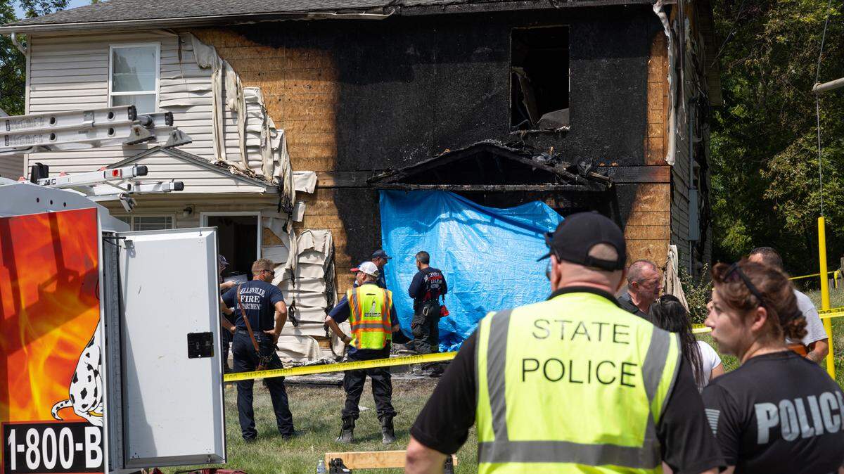 Investigators gather outside a duplex on South Seventh Street in Belleville on Sunday, after a vehicle crashed into it and set it on fire, killing two people. The driver has been charged with murder.