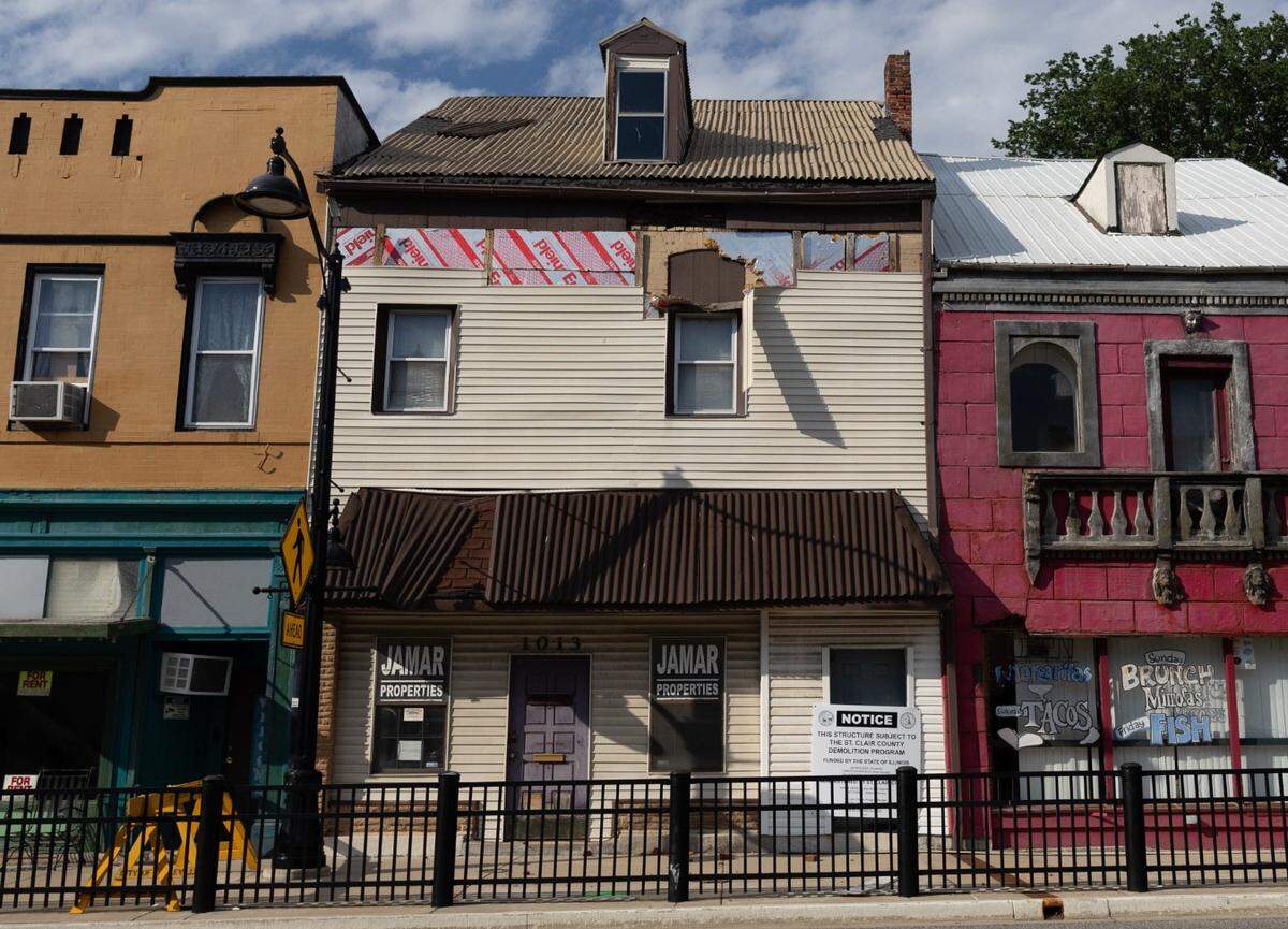 St. Clair County, on request from the city of Belleville, plans to demolish a storefront at 1013 W. Main St., center. The 2 1/2-story brick building is covered with tan vinyl siding that is peeling off.